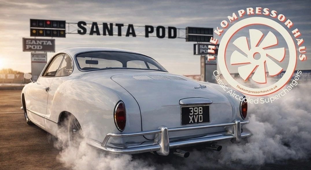 White Karmann Ghia laying a burnout under the Santa Pod start line gantry.